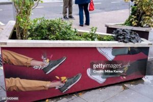 Two people showing off their men's sneakers outside by a bush. shoe carnival, comfort.