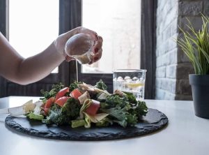 Woman pouring dip on her salad, a plant based meal