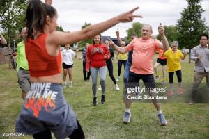 A Zumba instructor leading a class outdoors in a green field.