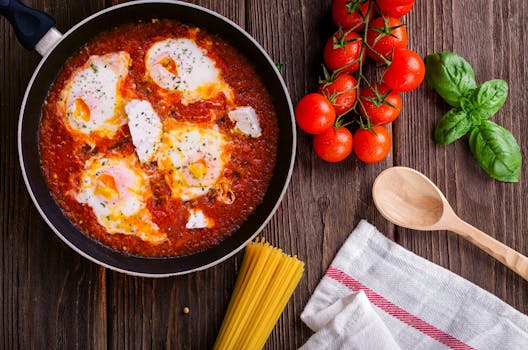 Delicious eggs in tomato sauce with basil, spaghetti, and fresh tomatoes on a wooden table.