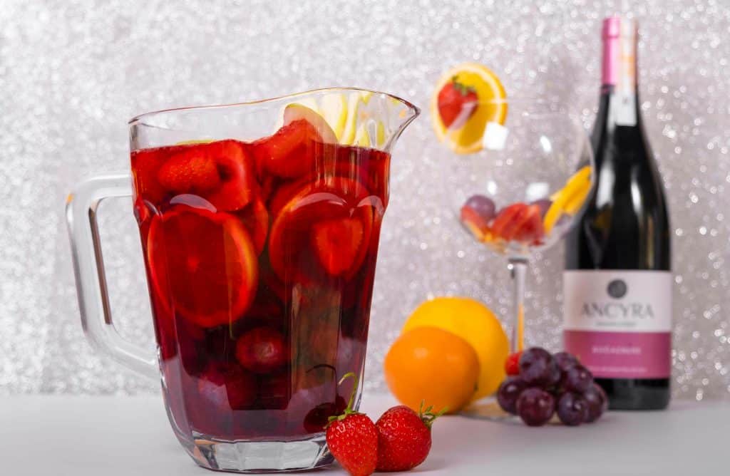 Vibrant sangria filled with fruits beside a wine bottle and glass, perfect for summer parties. Memorial day cocktails