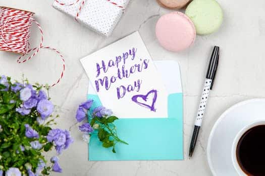 Creative Mother's Day card setup with flowers, coffee, and macarons on a marble table. Coupons