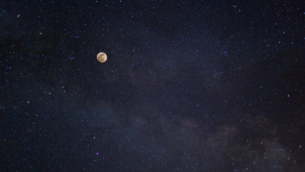 A breathtaking view of the full moon against a starry night sky with the Milky Way.
