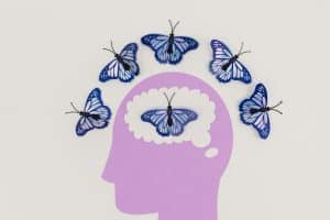 Creative illustration of butterflies symbolizing thoughts and transformation, fluttering over a brain silhouette—reflecting the journey of inner child healing and mental wellness.