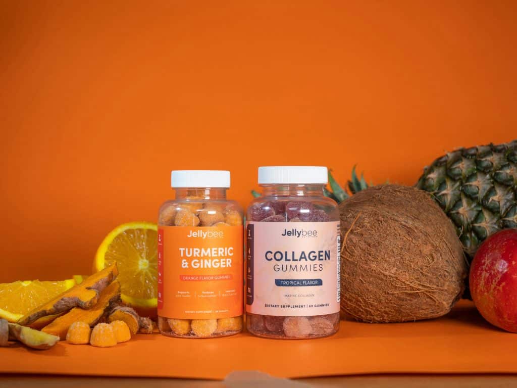 Colorful tropical beauty supplements in gummy form, surrounded by fresh fruits like coconut, pineapple, and orange.