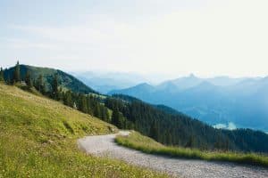 hiking lovers; a hiking trail on a grassy hill curving towards mountains in the distance