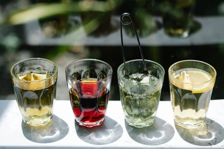 Four glasses of iced beverages in sunlight, showcasing colorful drink variety. summer drinks