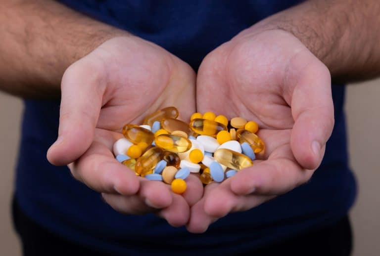 A person holding a handful of pills / vitamin patch