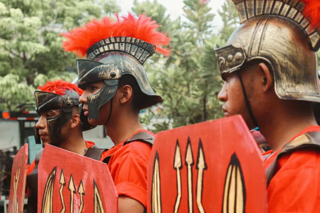 Men dressed as Roman warriors in a lively outdoor parade, daily devotion