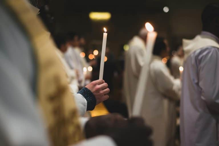 People holding candles in a solemn religious ceremony in a Roman church. Daily devotion
