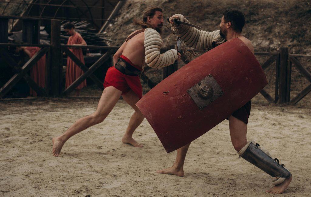 Two gladiators engaged in intense combat in a historical arena setting, daily devotion
