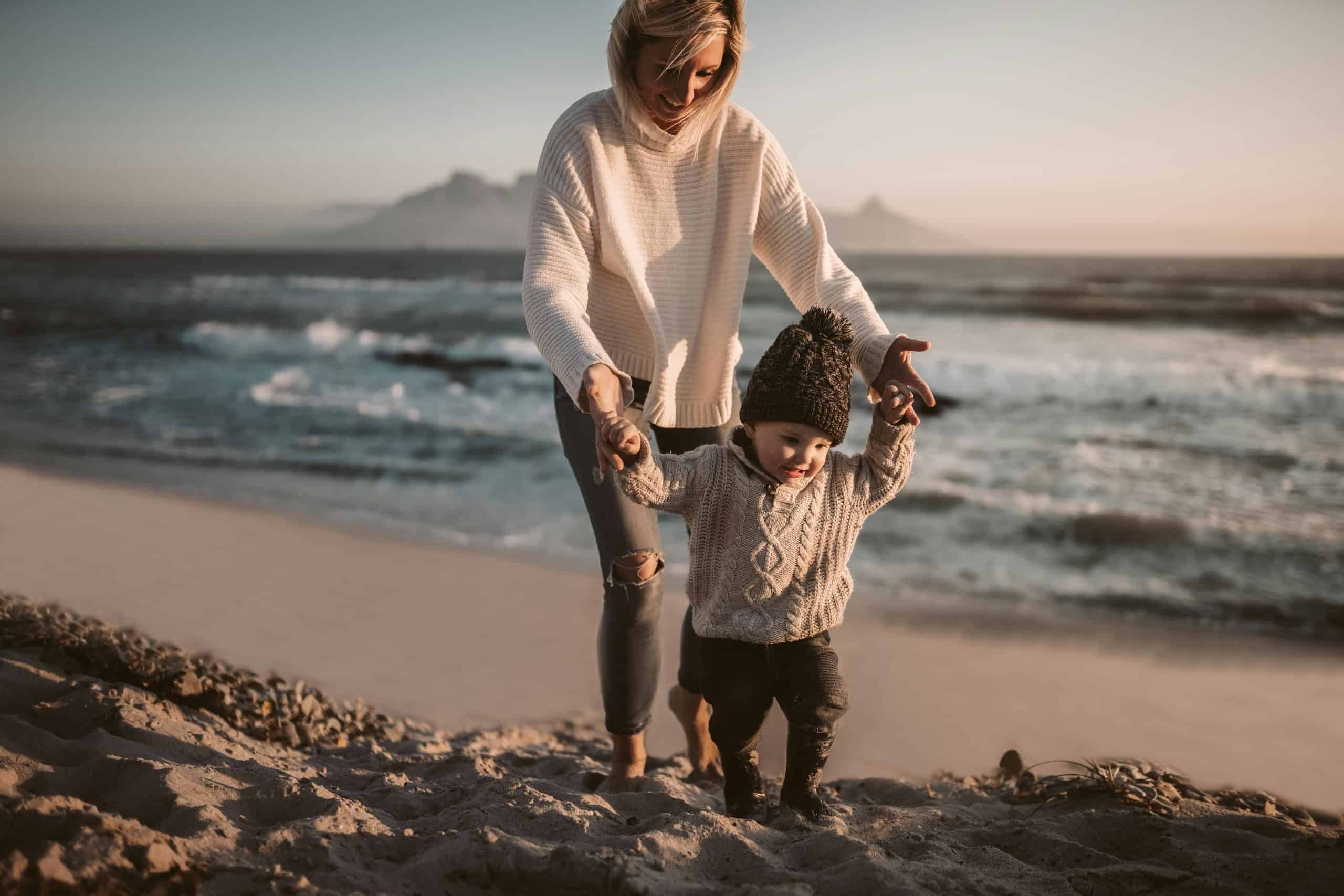 This photograph features a woman and a child enjoying the beach. East Coast beach town vacations can be fun in fall.