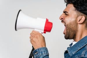 Close-up side view of a man shouting passionately into a megaphone, expressing urgency, Parenting philosophy