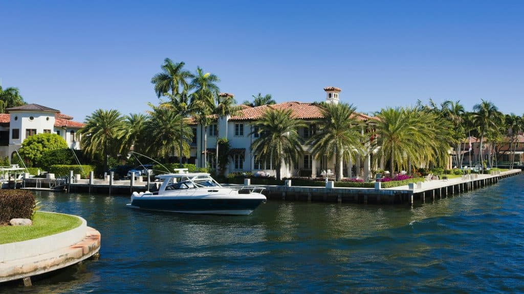 Stunning view of a luxury villa with boat in Fort Lauderdale's picturesque canal under a clear blue sky, daily devotion