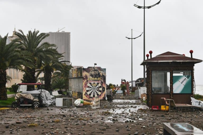 City street filled with storm debris and damaged structures under a cloudy sky., Jamaica