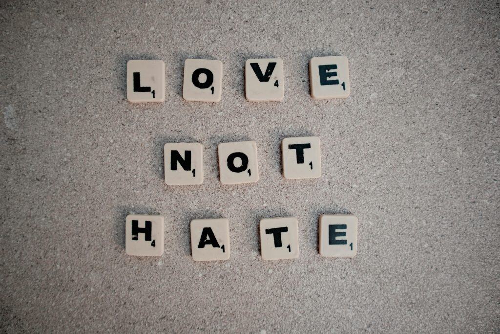 Scrabble tiles on pavement spelling the inspirational message 'Love Not Hate', daily devotion