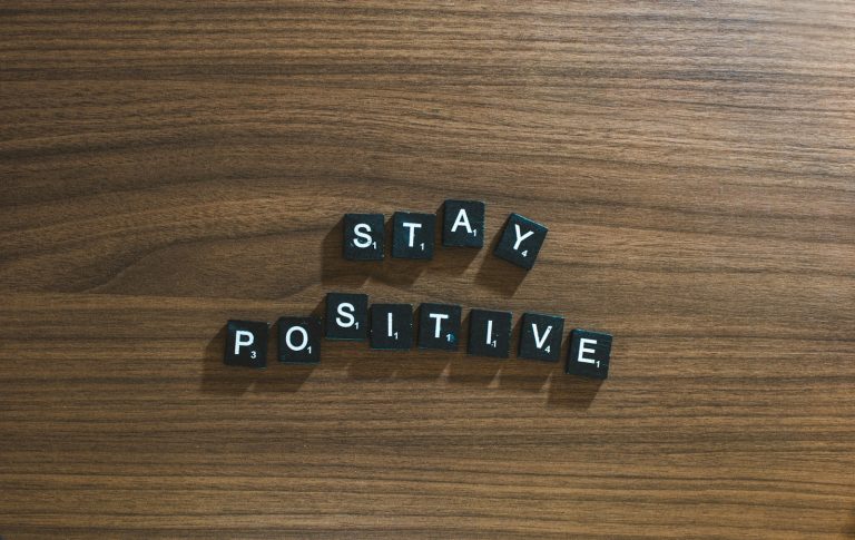 the word stay positive spelled in scrabble type on a wooden surface